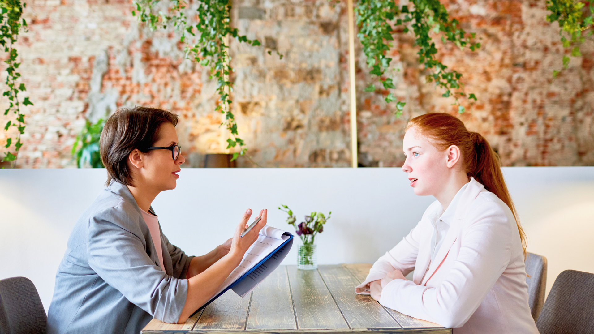 An interviewer and interviewee sitting at a wooden table 